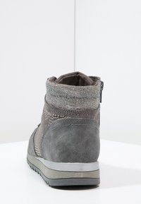 Šedá kotníková bota s texturovaným semišovým povrchem, kovově stříbrným lemem, šitými detaily a bočním zipem pro snadné nazouvání.