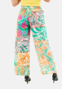 Pantalones de patchwork con una variedad de patrones florales y paisley en turquesa, rosa y naranja, con una cinturilla elástica y un diseño de pierna ancha.