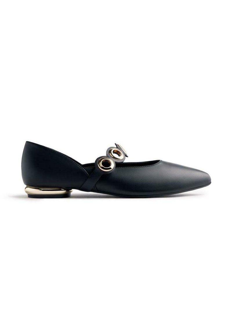 Black leather flat shoe with pointed toe, two large gold circular buckles on the strap, and a small gold-accented heel.