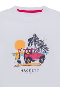 Camiseta blanca con un gráfico colorido de un jeep rosa, una tabla de surf y palmeras contra un fondo de atardecer. Logo de "Hackett London" debajo.