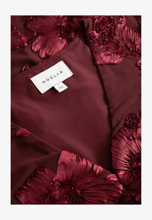 Burgundy fabric with three-dimensional, intricately textured floral embroidery. Tag visible with brand name "NOELLA" and size "S."