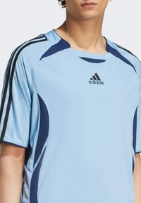 Light blue athletic jersey with navy accents. Features short sleeves, a ribbed texture, and the Adidas logo on the front.