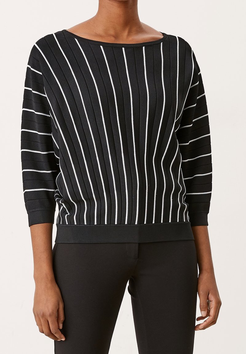 Czarny sweter w paski z białymi pionowymi liniami, dekolt łódka, rękawy 3/4 oraz ribbowany dół. Wykonany z teksturowanej, miękkiej tkaniny.