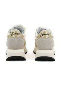 Beige Wildleder- und weiße Stoff-Sneaker mit einer klobigen Sohle. Goldene Akzente an der Ferse und im Logo. Schwarze Gummisohle. Verstellbare Schnürung.