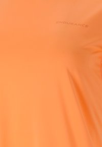 Orange idrottströja med en slät textur, med en subtil prägling av logotypen "ENDURANCE" över bröstet. Lätt och andningsbar design.
