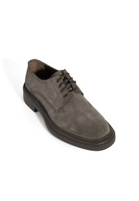 Chaussure de ville pour homme en daim marron avec lacets, dotée d'une épaisse semelle sombre, présentée sur un fond blanc.