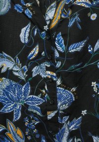 Camicia di tessuto nero con un motivo floreale caratterizzato da foglie blu e arancioni, rifinita con bottoni neri lungo la parte anteriore e un colletto.