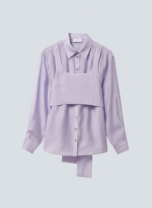 Λιλά πουκάμισο με μακρύ μανίκι και κουμπιά, με προσαρτημένο καβάλο cropped τοπ ως επικάλυψη και επιπλέον ύφασμα που κρέμεται κάτω από το τελείωμα του πουκαμίσου.