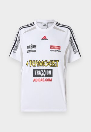 Λευκή αθλητική φανέλα με κοντά μανίκια, που διαθέτει μαύρες ρίγες στους ώμους. Πολλοί λογότυποι σε κόκκινο και κίτρινο χρώμα; υφή υφάσματος με λεία επιφάνεια.