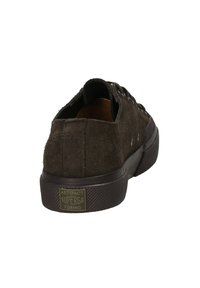 Sneaker basse in suede marrone scuro con suola in gomma spessa e etichetta "Artifact Superga Torino" sul tallone posteriore.