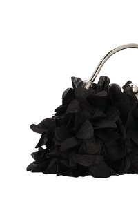 Bolso negro con tela texturizada y detalles superpuestos que parecen pétalos. El diseño se completa con un asa metálica y detalles metálicos.
