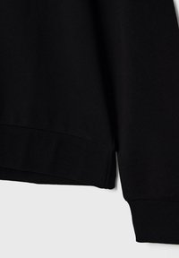 Sweatshirt noir avec poignets et ourlet côtelés, fabriqué en tissu doux et texturé, présentant un col rond classique et un design simple.