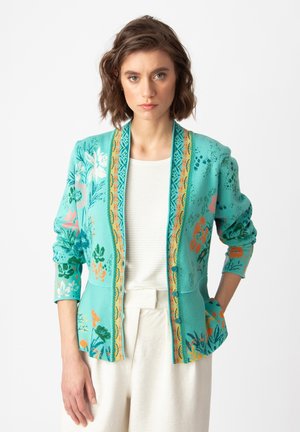 Turquoise knitted cardigan with floral pattern in green, orange, and white. Features long sleeves and a decorative orange trim along edges.