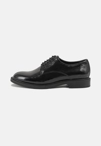 Scarpe eleganti in pelle nera con finitura lucida, punta rotonda e design con lacci. Presentano un tacco basso impilato e dettagli di cucitura discreti.