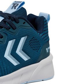 Ciemnozielony but sportowy z teksturowaną cholewką z dzianiny, jasnoniebieskimi akcentami, charakterystycznym wzorem pasków i białą podeszwą z amortyzacją.