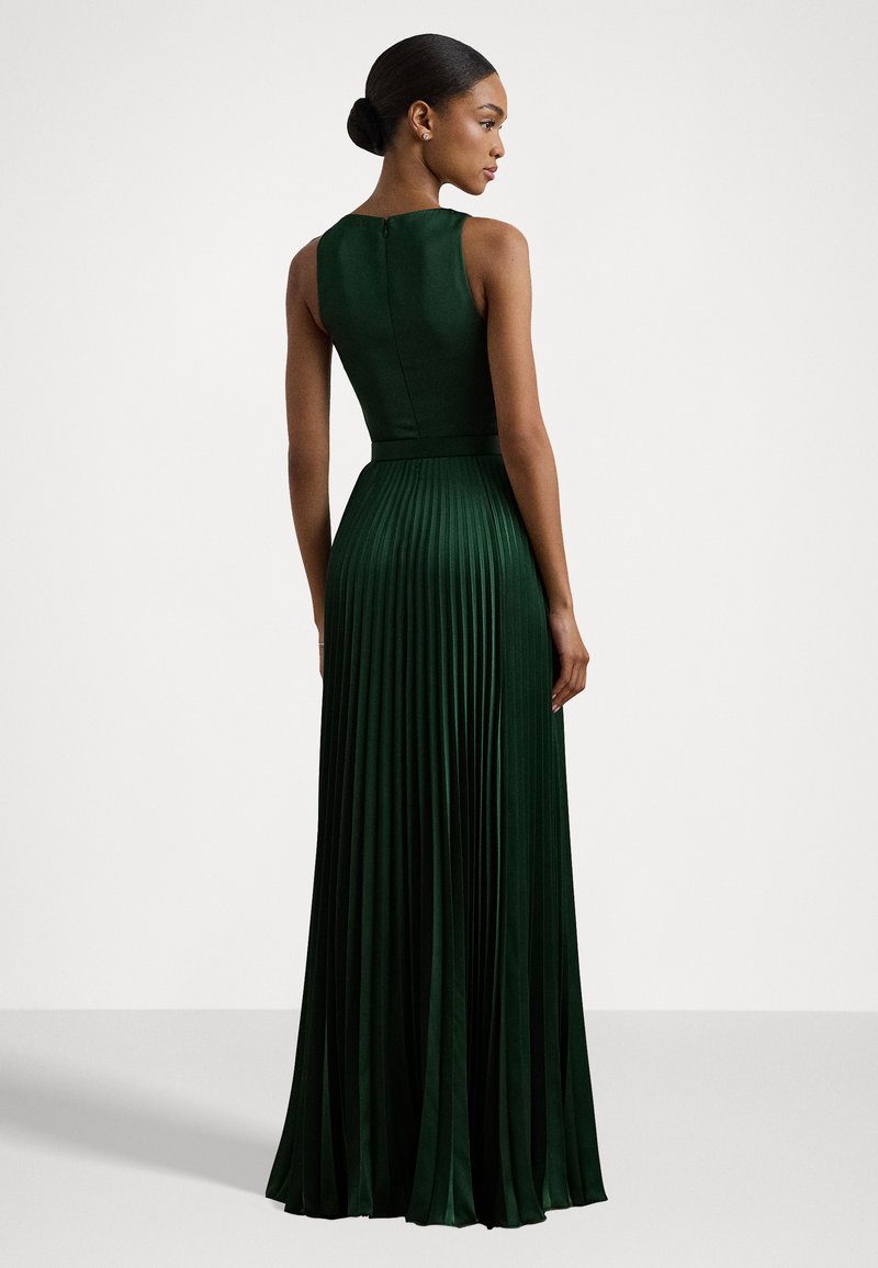 Grön, golv-lång klänning tillverkad av plisserat tyg. Har en figurnära bål med hög halsringning och en dold dragkedja bak.