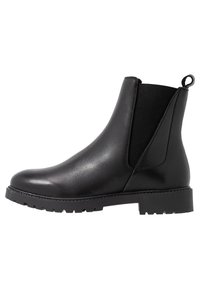 Svart läderankelboots med elastiska sidopaneler, dragflik, rundad tå och texturerad gummisula. Slät finish med minimal söm.
