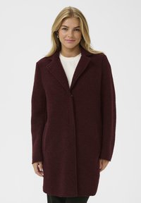 Burgundska volnena plašč s izrezanim ovratnikom, enojnim gumbom, dvema stranskima žepoma in dolgimi rokavi. Teksturiirana tkanina z mehak videzom.