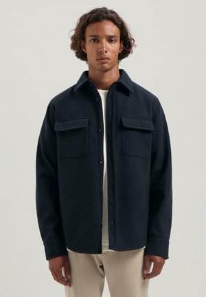 Marineblauwe button-up shirt met een kraag, twee borstzakken en een zacht gestructureerde stof. Heeft een relaxte pasvorm en lange mouwen.