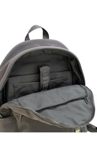 Interno di uno zaino grigio con tasca con zip, cinghie in tessuto e texture in nylon liscia. Chiusura con doppia zip e maniglia superiore per il trasporto.