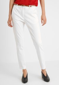 Vita skräddarsydda byxor med slim fit, med platt front, bältestroppar och subtila veckdetaljer, kombinerat med svarta högklackade skor.
