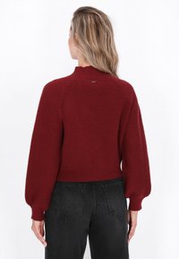 Burgundowy sweter prążkowany z wysokim kołnierzem i balonowymi rękawami; teksturowana dzianina; krótki krój; detal metki przy szyi.