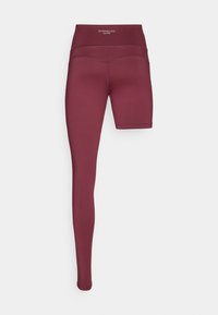 Leggings de sport bordeaux avec une coupe ajustée, une taille haute et une jambe plus courte. Fabriqués en tissu extensible et respirant qui évacue l'humidité.