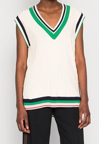 Haut sans manches crème côtelé avec un décolleté en V profond, ornée de rayures vertes et bleu marine le long de l'encolure et de l'ourlet, offrant un design décontracté.