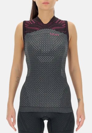 Woman wearing a sleeveless black and pink textured athletic top with geometric patterns standing with arms relaxed.