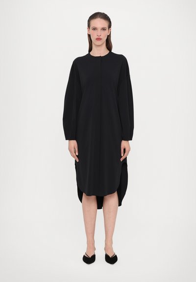 Vestido negro de manga larga con escote redondeado, aberturas laterales y un corte relajado. Hecho de una tela suave con un acabado mate.