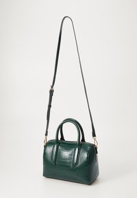 Sac à main en cuir synthétique à texture de crocodile, de couleur vert foncé, avec une forme structurée, deux poignées supérieures et une bandoulière amovible. Quincaillerie en ton doré.