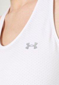 Weißes Sport-Top aus strukturiertem Stoff, mit rundem Ausschnitt und einem kleinen grauen Logo auf der linken Brust.
