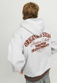 Sudadera con capucha gris que presenta texto gráfico rojo en la espalda, con puños y dobladillo acanalados. Confeccionada en una mezcla de algodón, tiene un corte relajado.