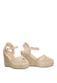 Sandalias de cuña beige con parte superior de yute tejido, punta abierta y correa en el tobillo ajustable. Presenta un patrón texturizado y una plataforma elevada.