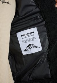 Bežna flis jakna s črnim notranjim podom. Ima etiketo z napisom "PEGADOR" in grafiko gore, kar označuje blagovno znamko oblačil za zunanjo uporabo.