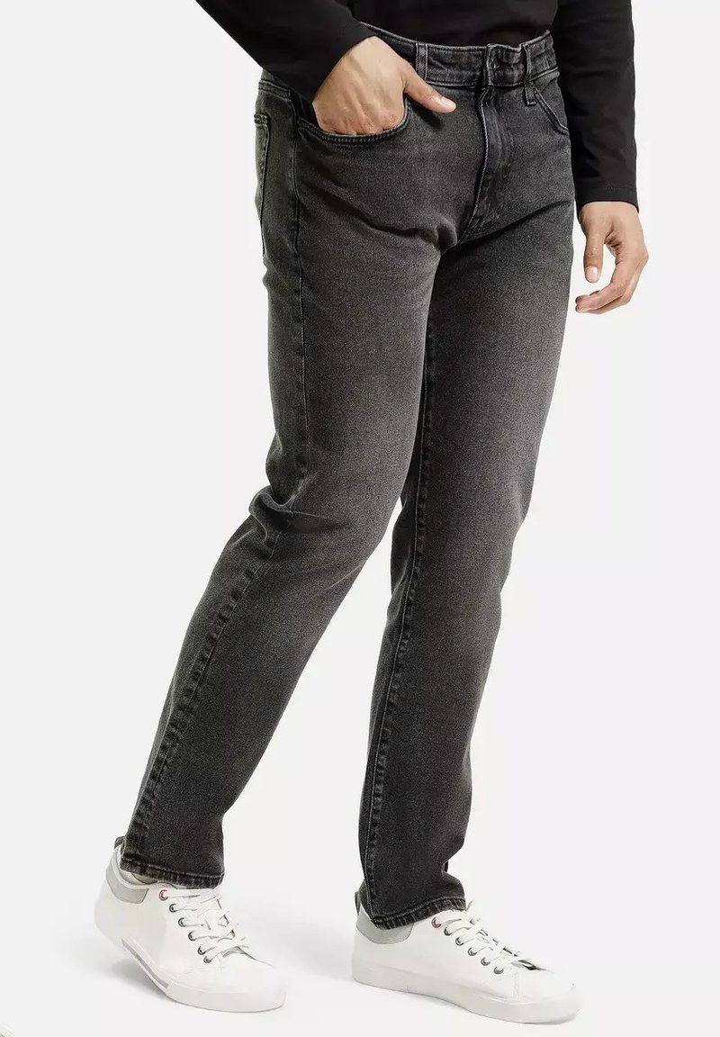 Szare dżinsy o prostym kroju, pięć kieszeni i klasyczny design pasa, noszone z białymi trampkami.