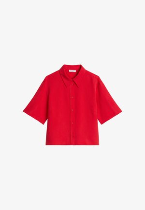 Chemise rouge vif à manches courtes avec col pointu et coupe légèrement carrée et courte sur fond blanc.