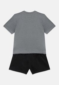 Γκρι βαμβακερό t-shirt με κοντά μανίκια και μαύρο βαμβακερό σορτς. Και τα δύο κομμάτια έχουν απλό σχέδιο και άνετη εφαρμογή, με ραμμένες ραφές.