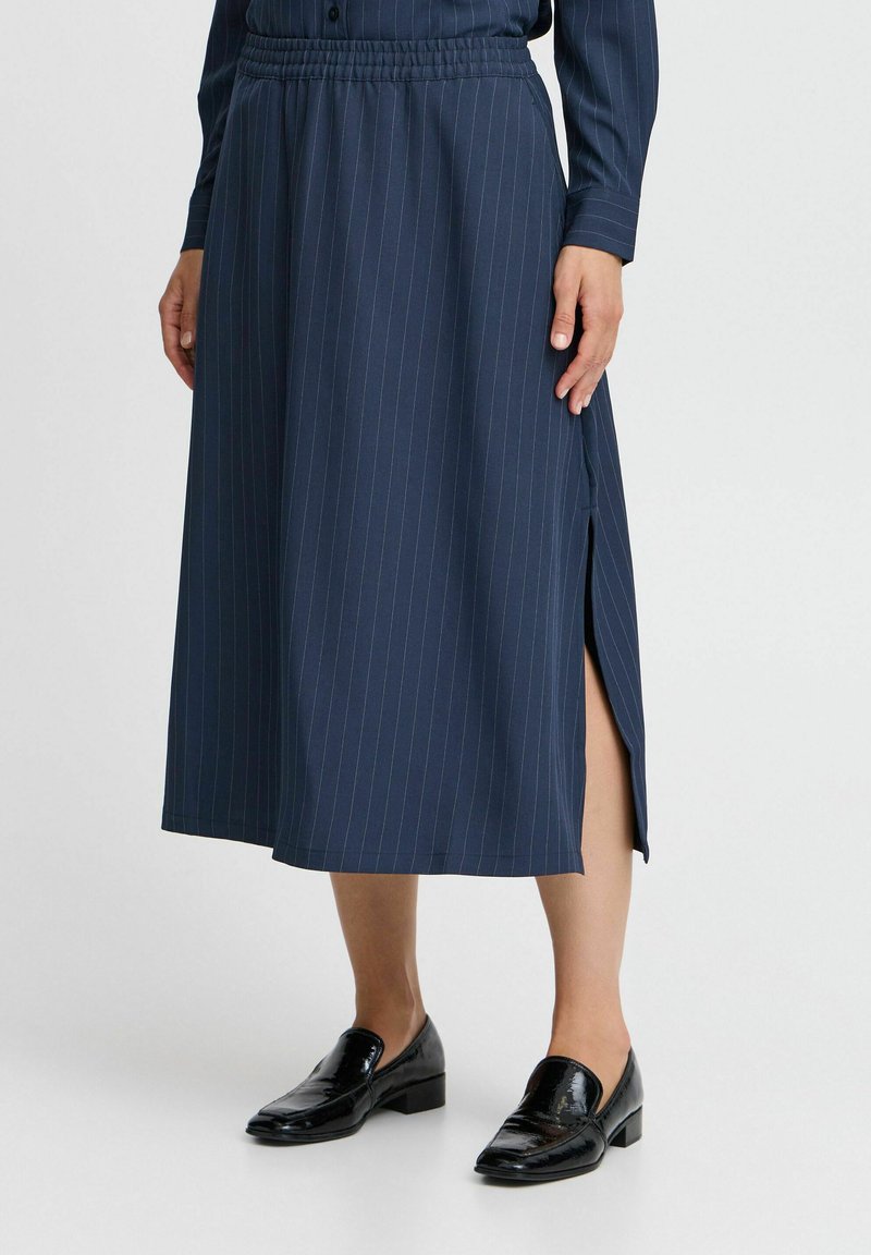 Jupe midi bleu marine avec des rayures verticales, taille élastique et fentes latérales. Porte avec des mocassins noirs brillants. Texture lisse.