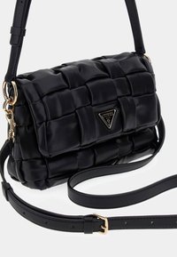 Borsa a mano trapuntata nera realizzata in pelle sintetica, con una placca logo in tono oro, tracolla regolabile e superficie texture.