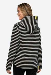 Haut à rayures en bleu marine et crème, fabriqué en tissu doux. Il possède une grande capuche, des manches longues et une accentuation jaune près de l'ourlet.
