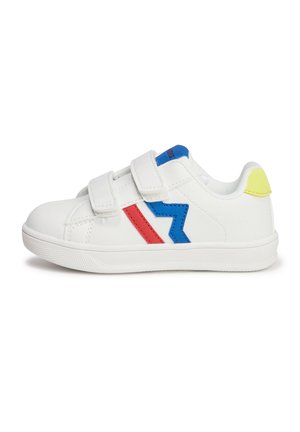 Baskets blanches avec des bandes Velcro, ornées d'accents en zigzag bleu et rouge et d'une languette de talon jaune, en matériau synthétique.