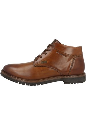 Botte chelsea en cuir marron avec un bout rond, un laçage à l'avant et une semelle en caoutchouc texturée. Présente un logo discret sur le côté.