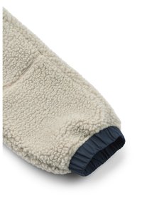 Krém színű bolyhos pulóver, textúrával és puha felülettel, sötétkék rugalmas mandzsettával. Elöl zsebes zsebe van.