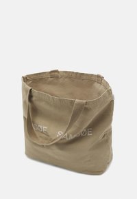Kaki bomull tote-veske med doble stofferhåndtak; har trykt hvitt logo på den ene siden; myk tekstur, åpen topp og romslig interiør.