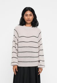 Helles rosa Sweater aus weichem, strukturiertem Stoff mit schwarzen horizontalen Streifen. Besitzt einen runden Ausschnitt und lange, weite Ärmel.
