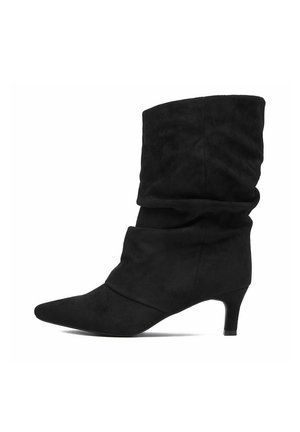 Stivale nero a metà polpaccio con punta appuntita e tacco basso kitten, realizzato in materiale morbido simil suede su sfondo bianco.