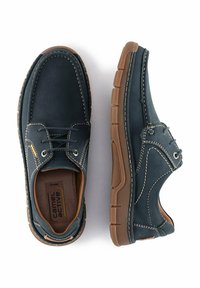 Dunkelblaue Ledersneaker mit braunen Akzenten. Ausgestattet mit einer Schnürung, gesteppten Details und einer strukturierten Gummisohle.
