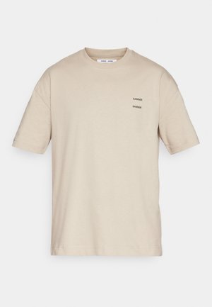 T-shirt en coton beige avec un col rond, des manches courtes et trois petits logos de marque imprimés en noir sur le côté gauche.