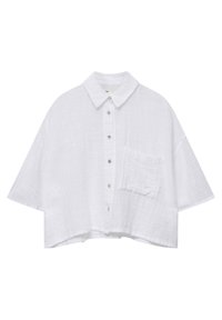 Chemisier court blanc en tissu texturé, avec un col classique, des manches courtes et une poche avant avec fermeture à bouton.